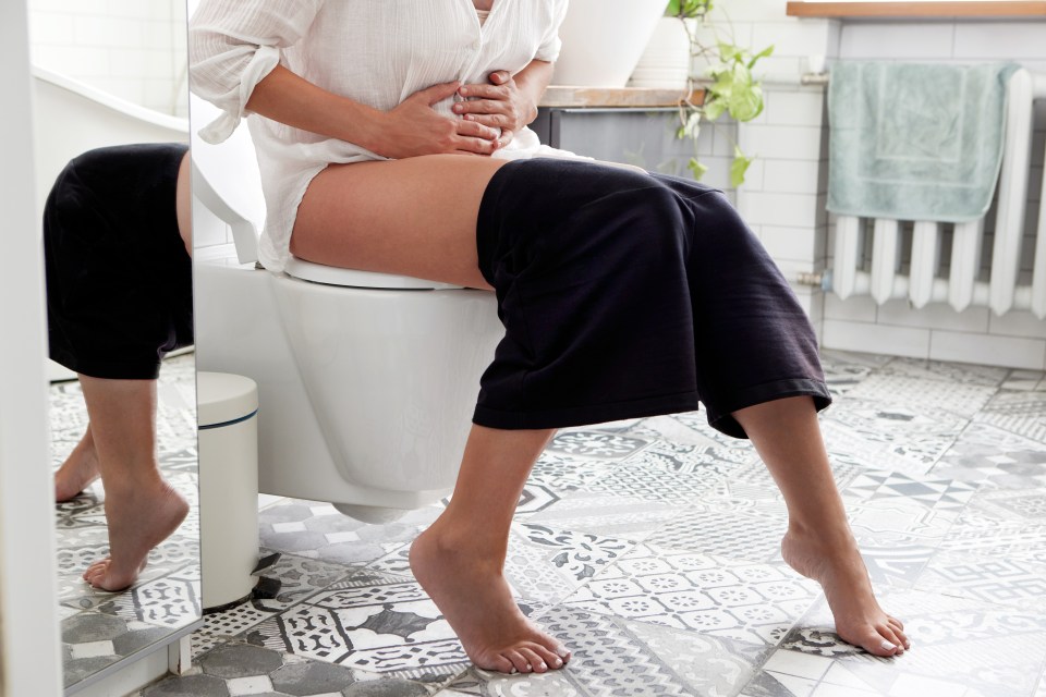 Woman experiencing diarrhea in a bathroom.