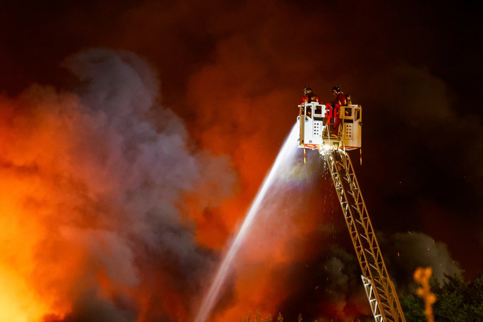 Firefighters extinguishing a fire from a ladder truck.