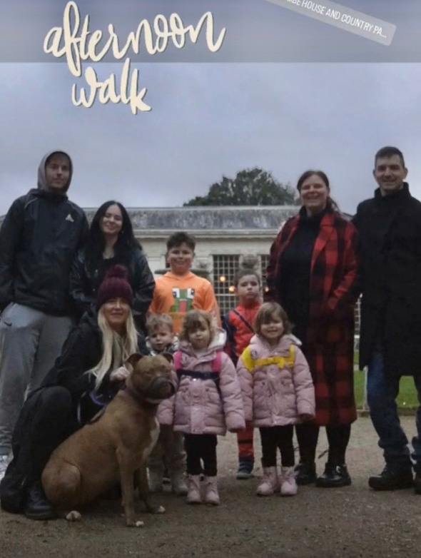 Group photo of a large family and their dog on an afternoon walk.