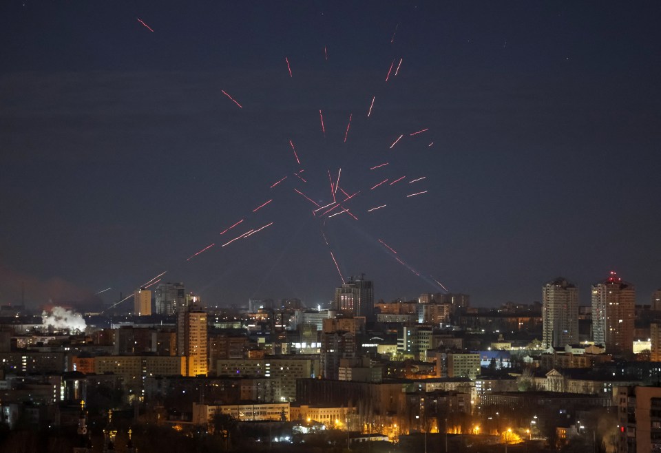 Nighttime view of Kyiv, Ukraine, with tracers and searchlights in the sky during a Russian drone strike.