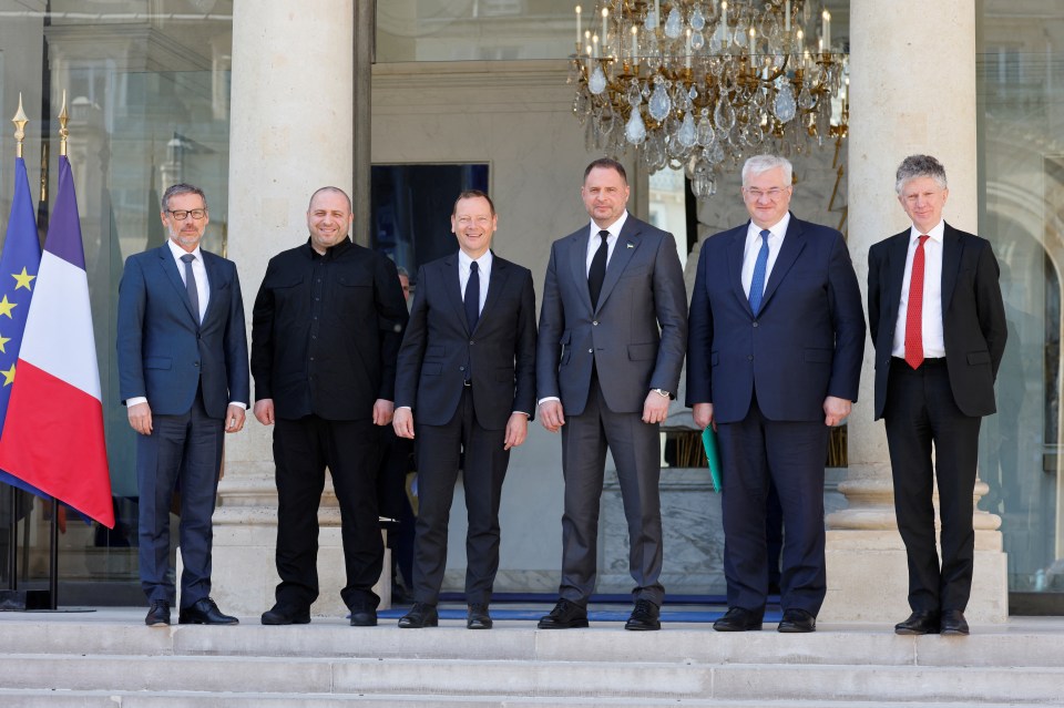 Group photo of six men in suits standing on the steps of a building.