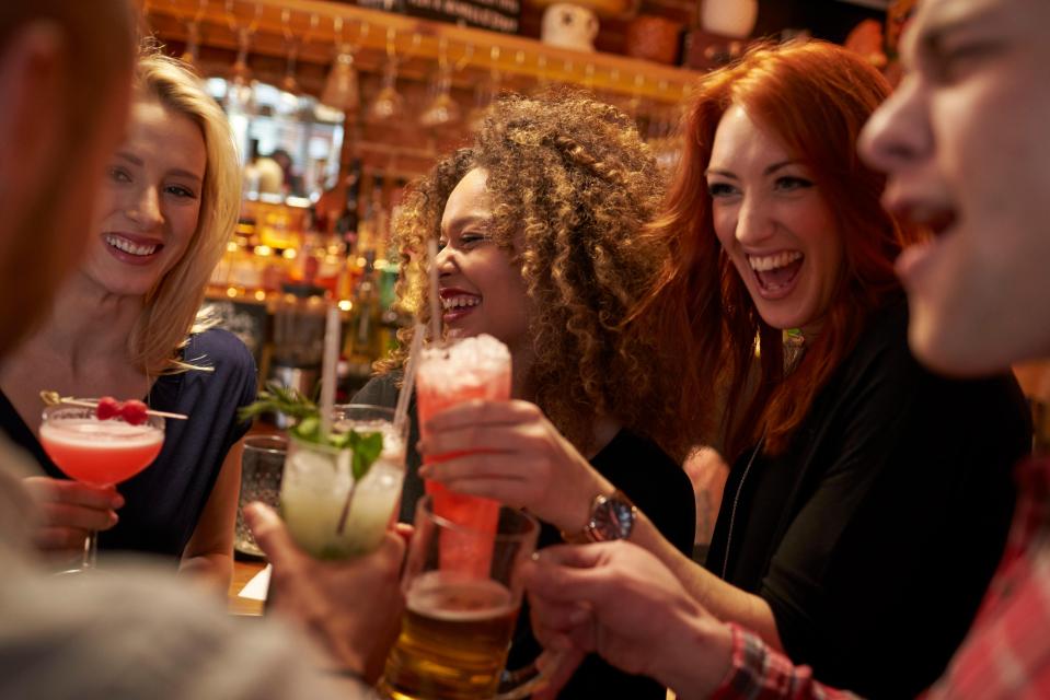 Friends toasting drinks at a bar.