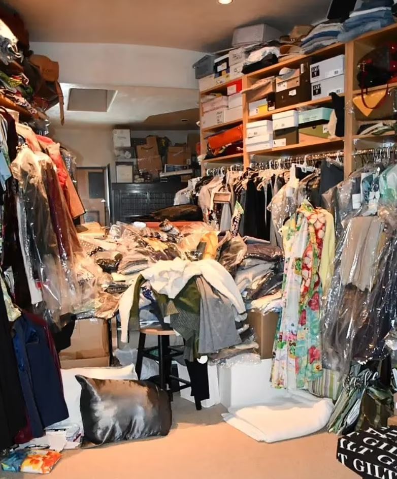 Overstuffed room with piles of clothes and belongings.
