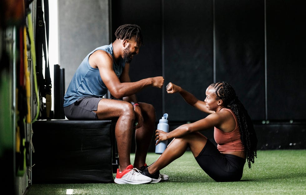 two individuals engaged in a fist bump while seated in a gym environment