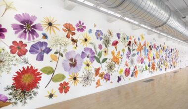 a large, full-wall installation of numerous flower painting cutouts that resemble giant pressed flowers all along a white wall