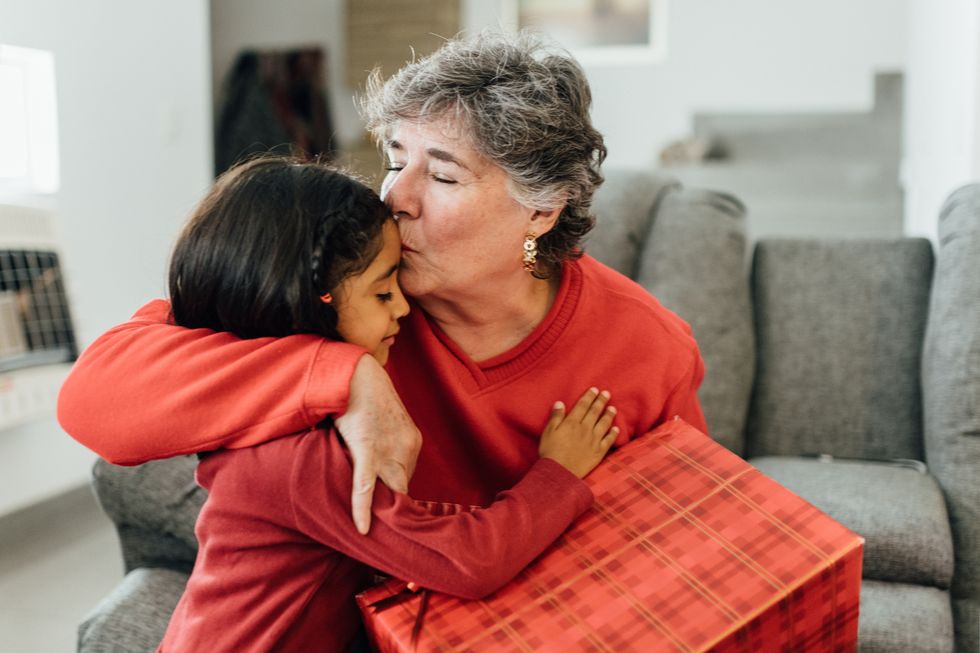 Grandparent embraces grandchild and gives them a gift