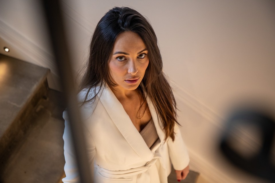 Woman in white blazer looking at camera.