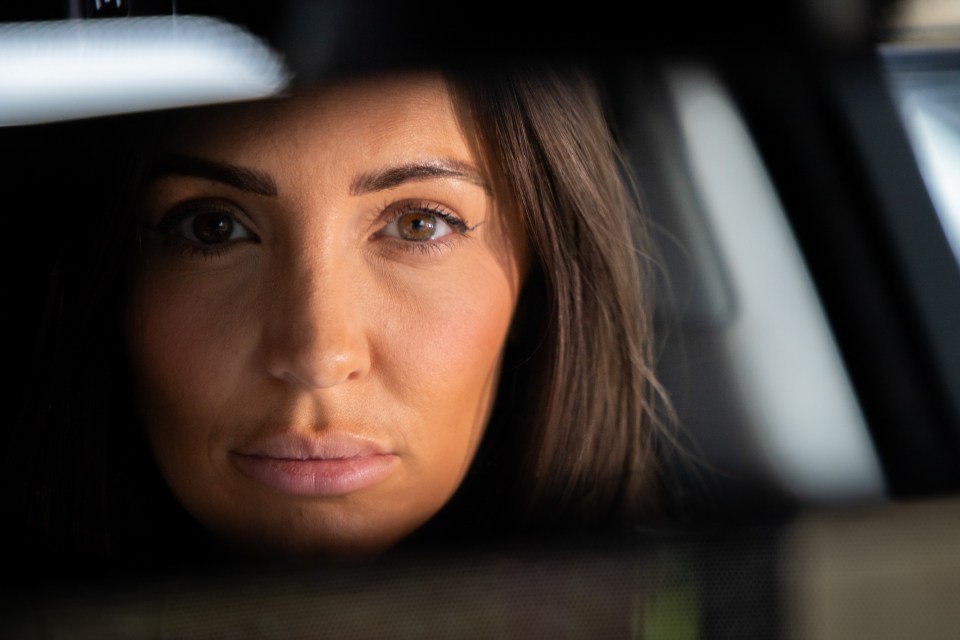 Close-up of a woman's face reflected in a rearview mirror.