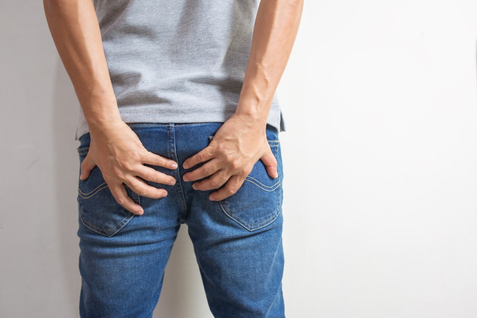 Person holding their buttocks in pain.
