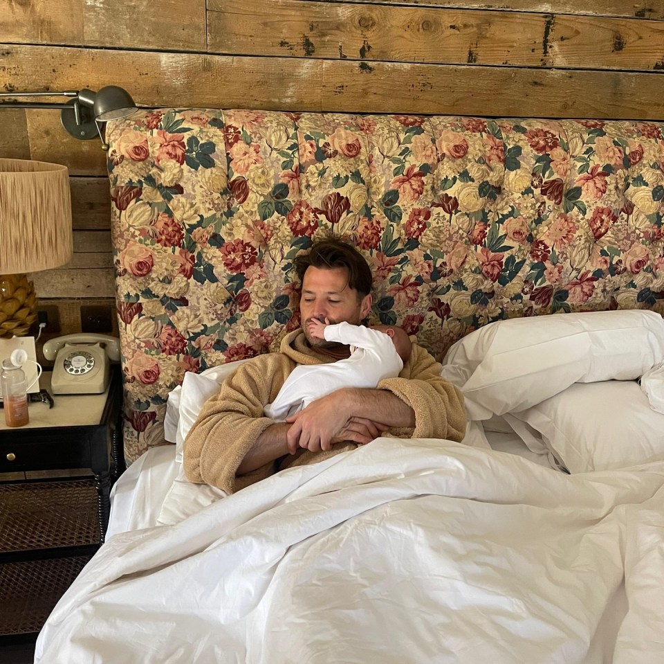 Man in a robe holding a baby in bed.