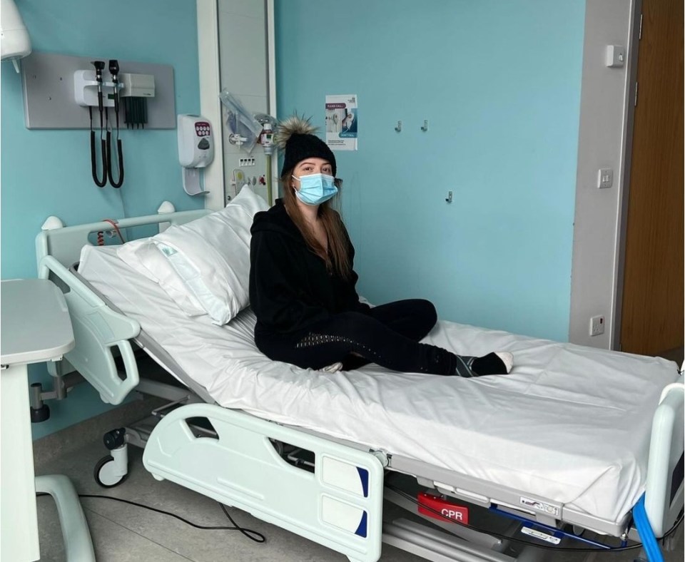 Woman wearing a facemask sitting on a hospital bed.
