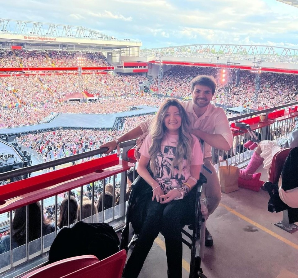 Woman in wheelchair with a man at a stadium concert.