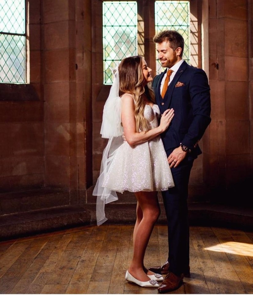A bride and groom embracing in a stone building.