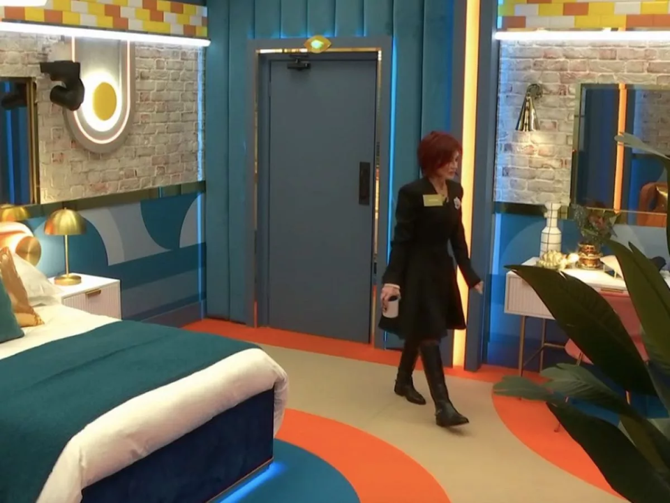 Woman in a black coat walking through a brightly colored room.
