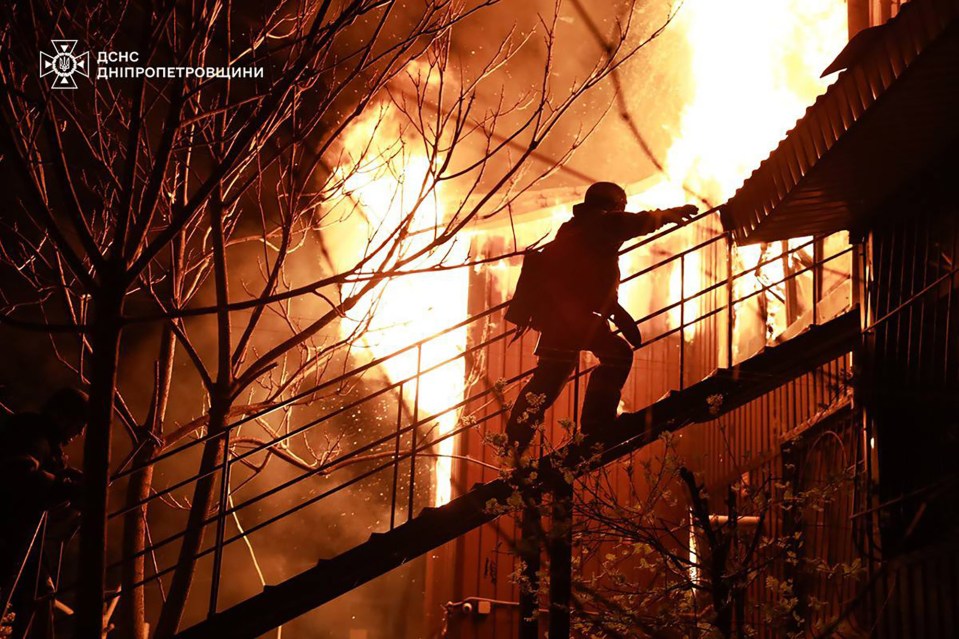Firefighter ascending a staircase during a building fire.