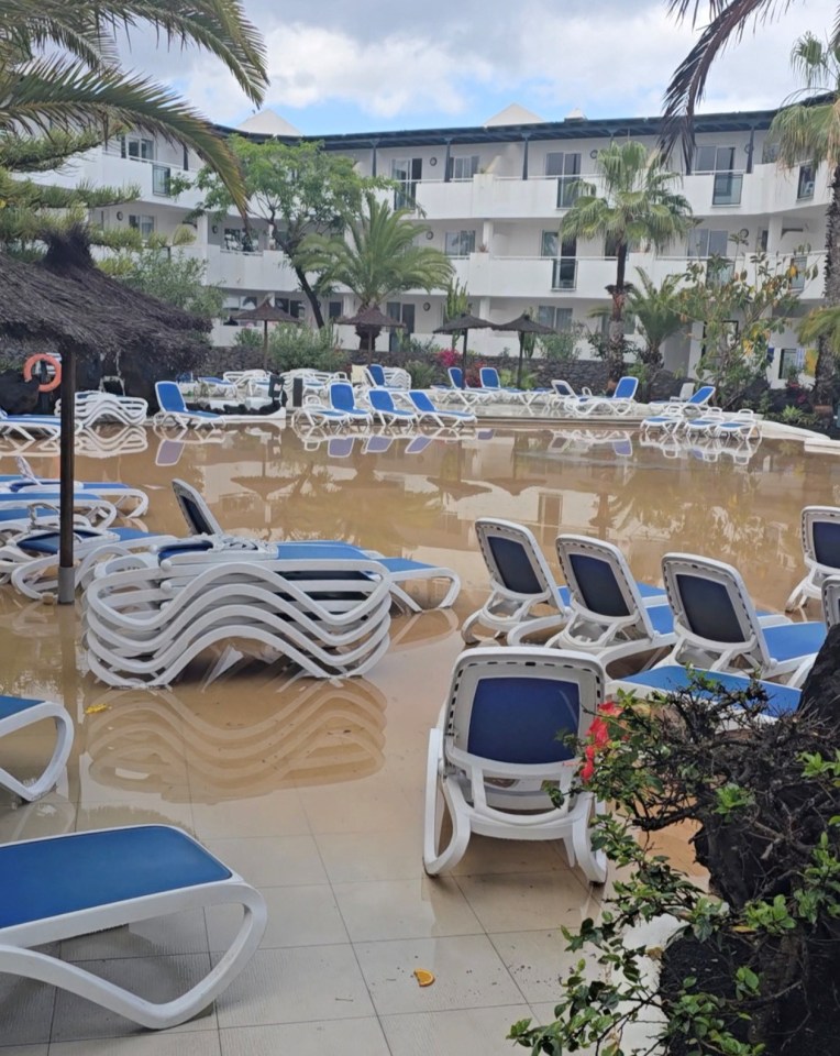 Flooded resort pool with lounge chairs.