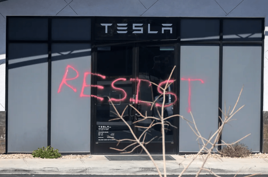 Tesla store entrance with "RESIST" spray-painted on the glass doors.