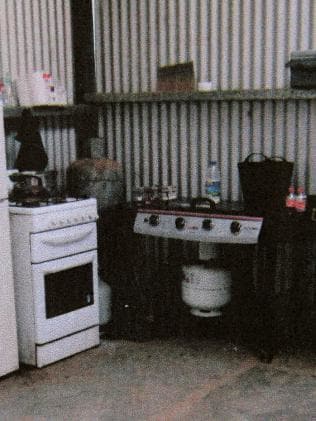 A small kitchen with a white oven and a portable gas stove.