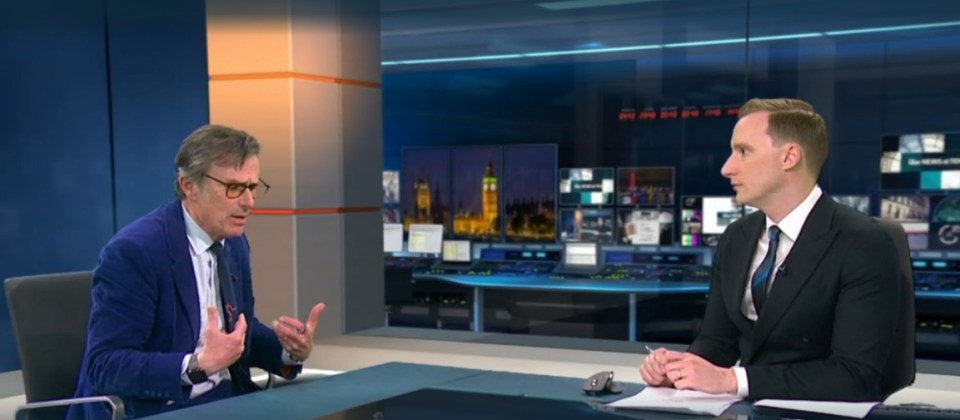 Two news presenters sitting at a desk in a television studio.