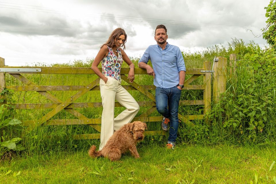 Jimmy and Shivi leaning on a wooden gate with their dog.
