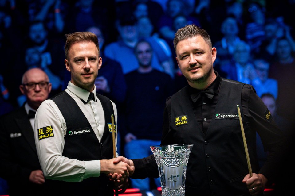 Judd Trump and Kyren Wilson shaking hands before a snooker final.