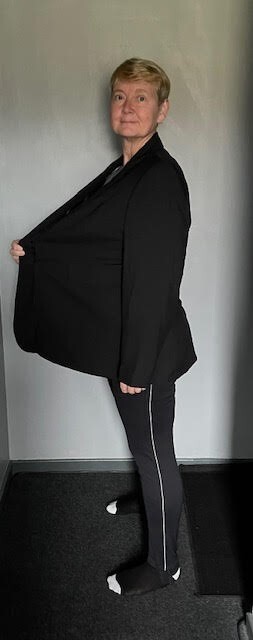 Woman in black blazer and pants after weight loss.