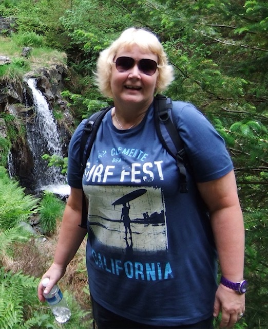 Woman standing in front of a waterfall, holding a water bottle.