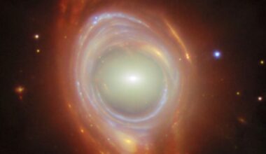 A spiral galaxy with a bright, glowing core and swirling, luminous rings surrounded by dark space and numerous tiny stars. The rings exhibit subtle colors, giving a sense of depth and motion.