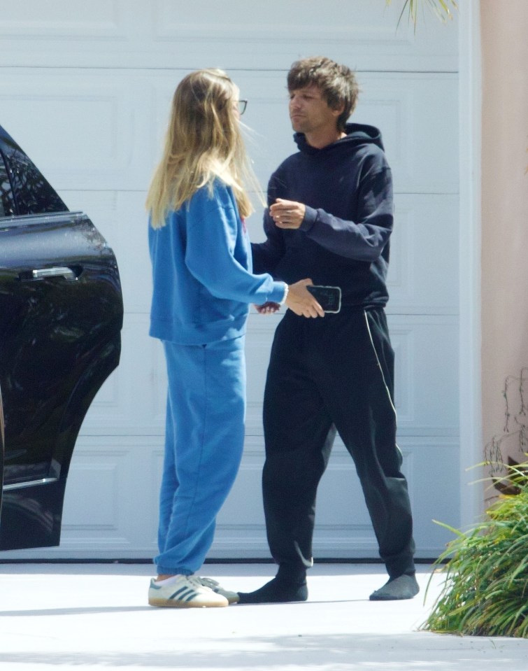 Louis Tomlinson and Zara McDermott holding hands.