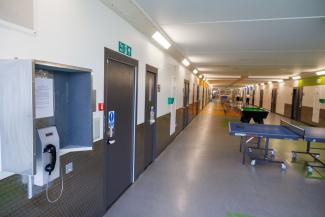 View down a prison hallway with a telephone and recreational facilities.