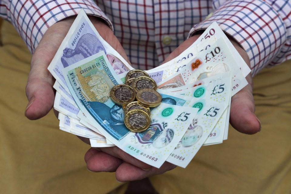 Hands holding British pound notes and coins.