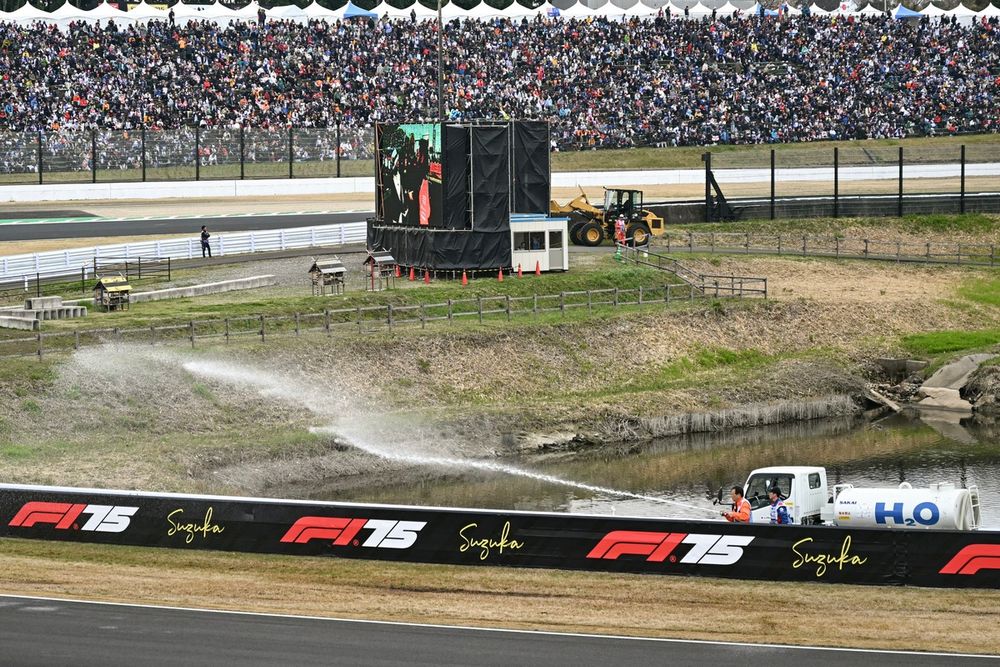 Marshals spray water to dampen the grass to prevent trackside fires