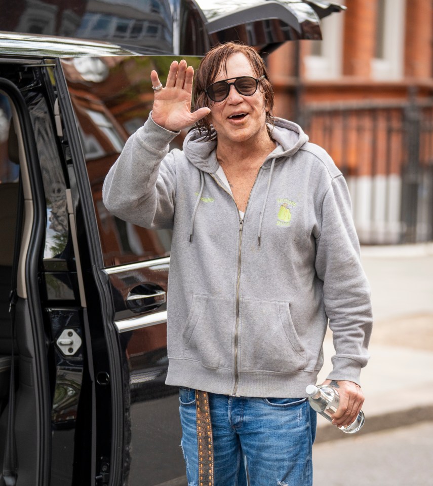 Mickey Rourke waving goodbye near a car.