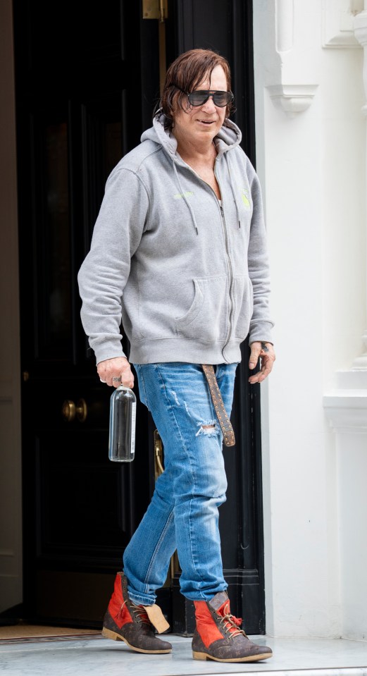 Mickey Rourke leaving a hotel in London, carrying a bottle.