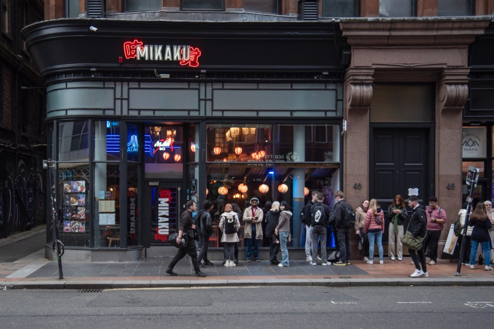 Mikaku restaurant storefront with people waiting in line.