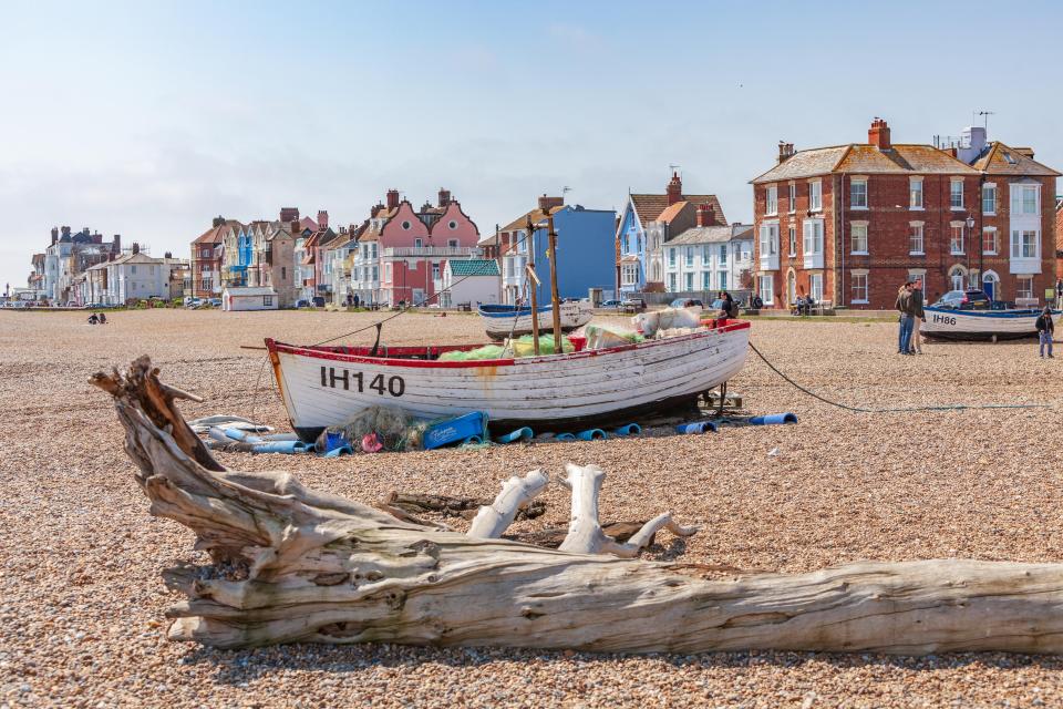 Fishing boat on a pebbled beach in front of houses.