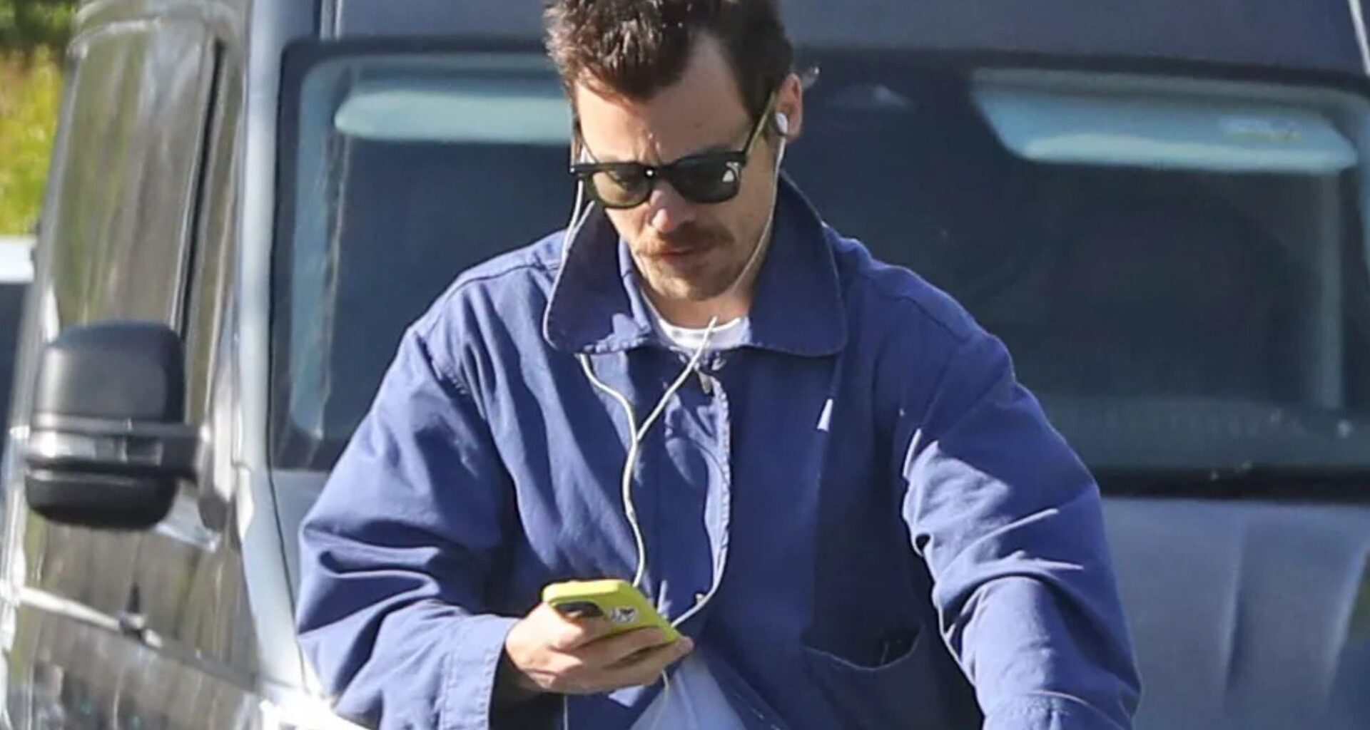 Pop star Harry Styles looks down at phone while riding electric bike without helmet on busy London road