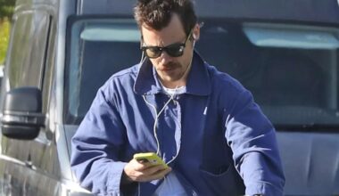 Pop star Harry Styles looks down at phone while riding electric bike without helmet on busy London road