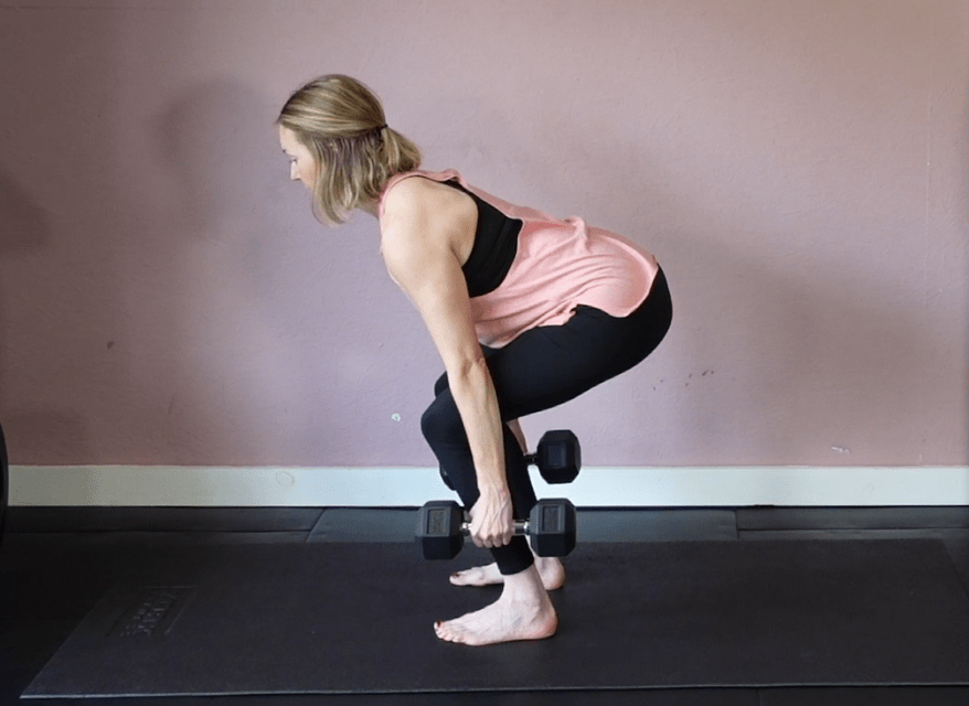 Woman performing a dumbbell squat.