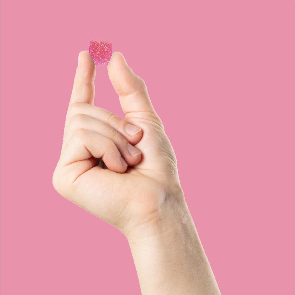 Hand holding a pink gummy candy.