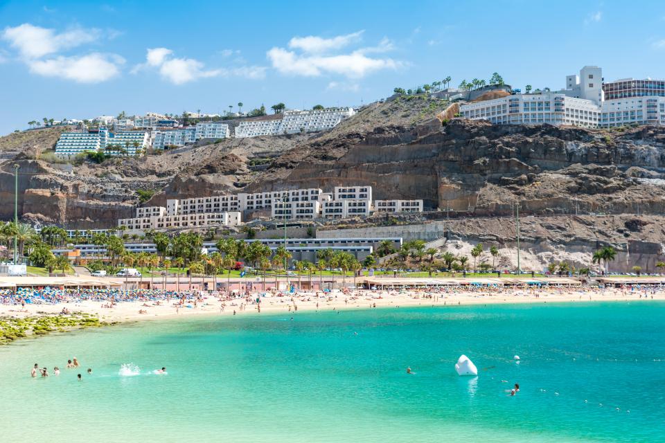 Beach Amadores in Gran Canaria, Spain, with hotels on a cliff overlooking a sandy beach and turquoise water.