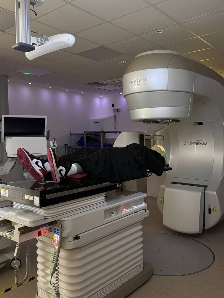 Person lying on a radiotherapy table during treatment.