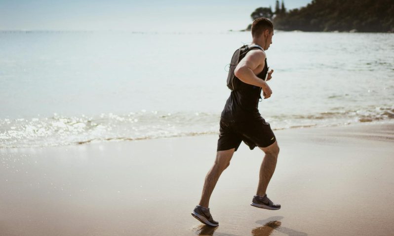 Man running with headphones on beach