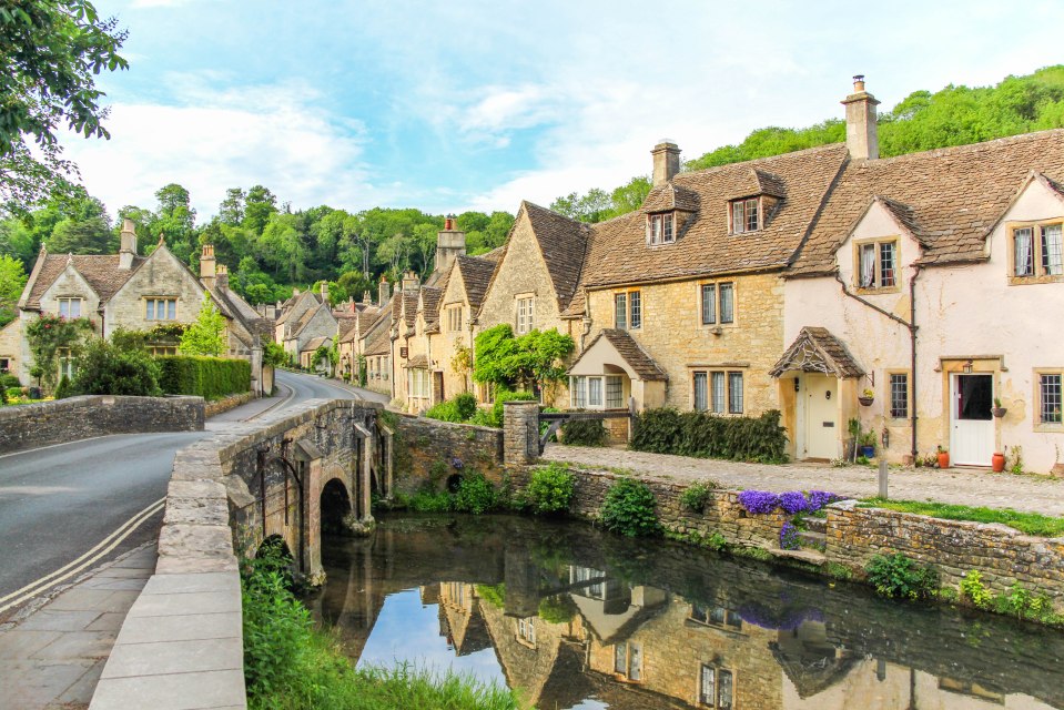 Picturesque Cotswold stone cottages reflected in a river.