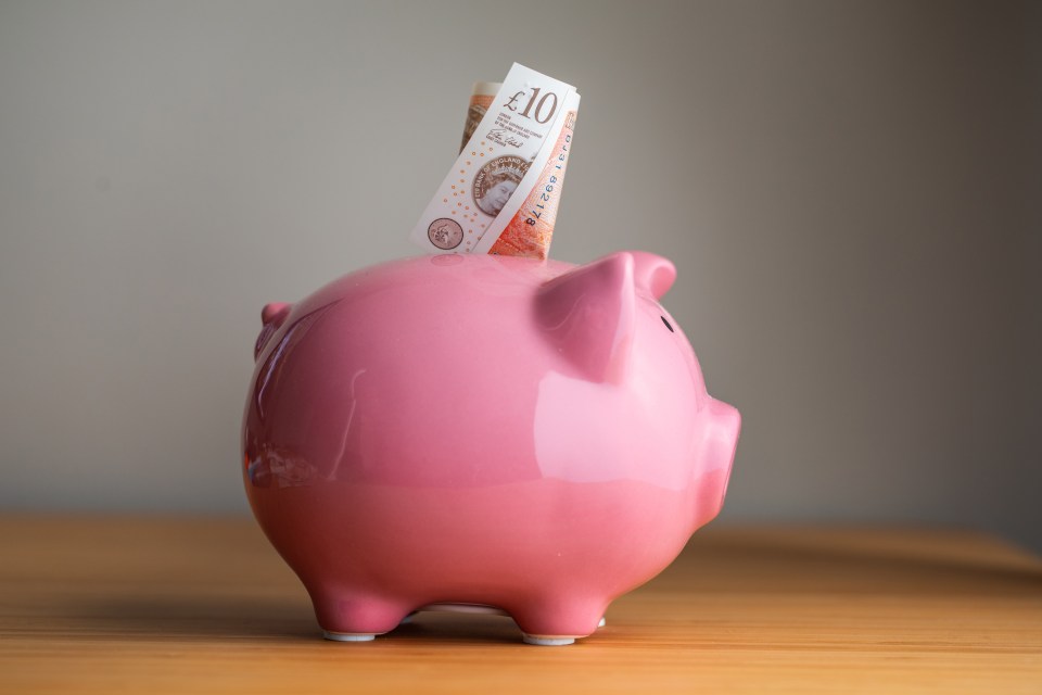 Pink piggy bank with a ten-pound note inserted.