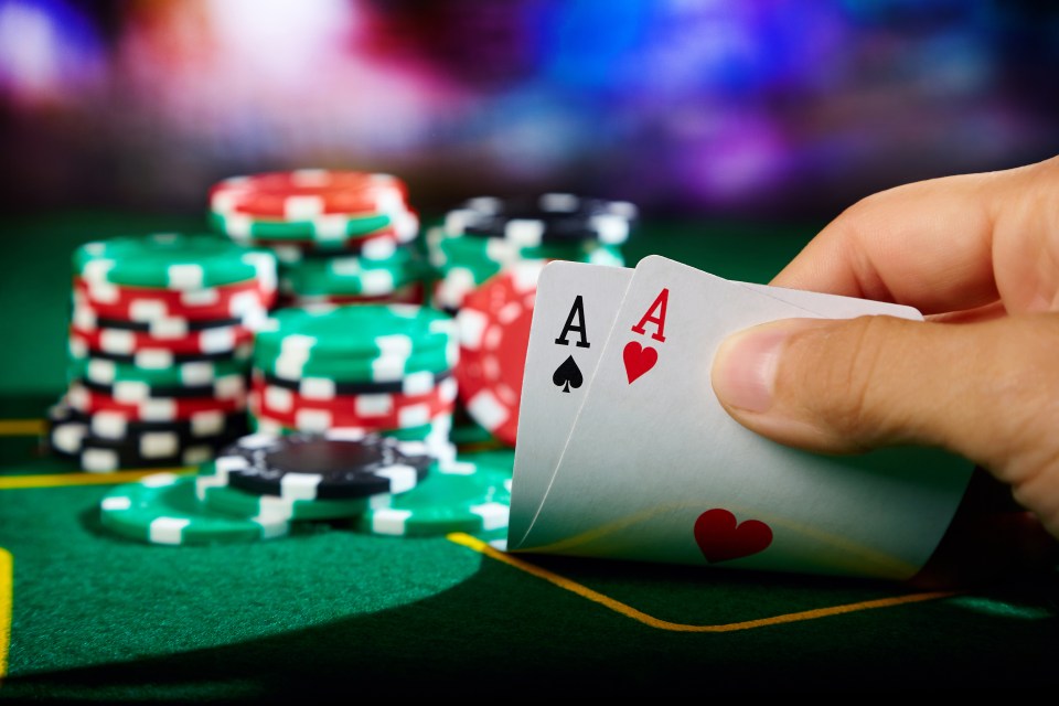 A hand revealing a pair of aces at a poker table.