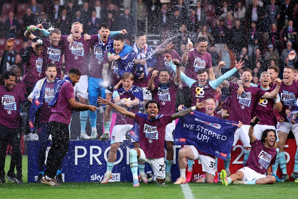 Burnley football players celebrating promotion to the Premier League with champagne.