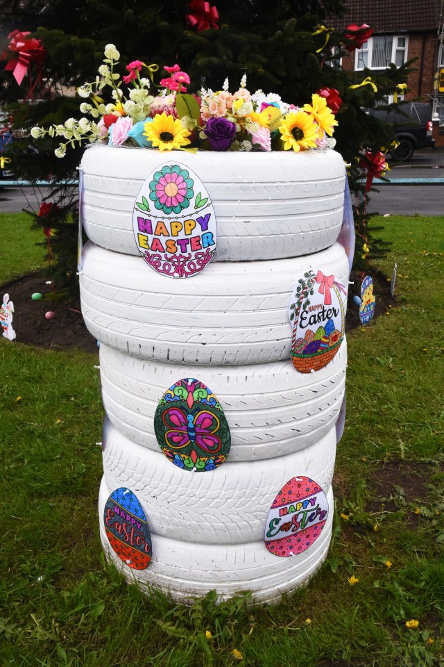 Easter memorial made of stacked tires decorated with flowers and Easter-themed decorations.