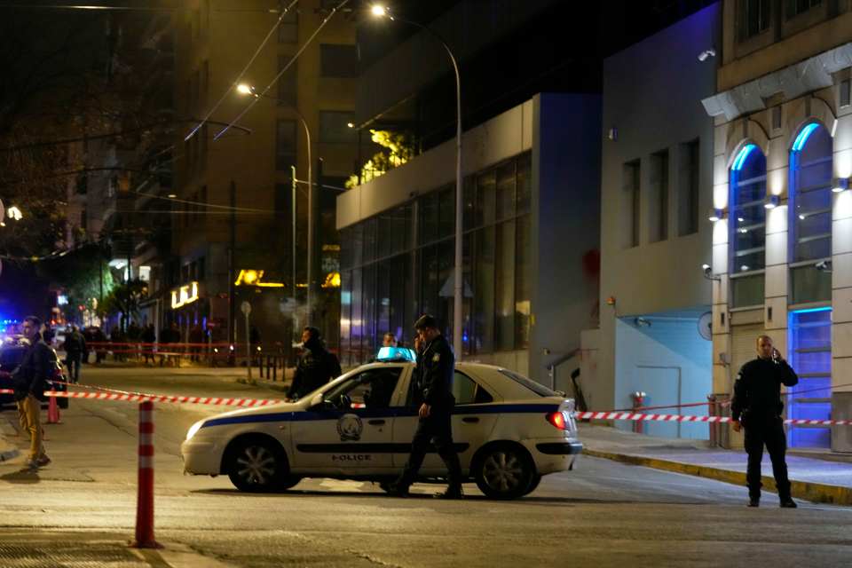 Police officers close a road following a suspected bomb explosion near Hellenic Train offices in Athens.