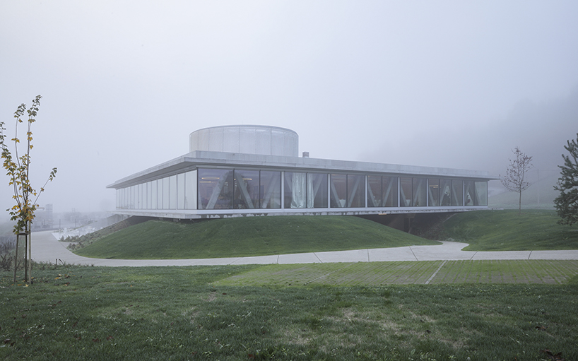 horizontal disk anchors office building by MVA on three greened mounds near zagreb